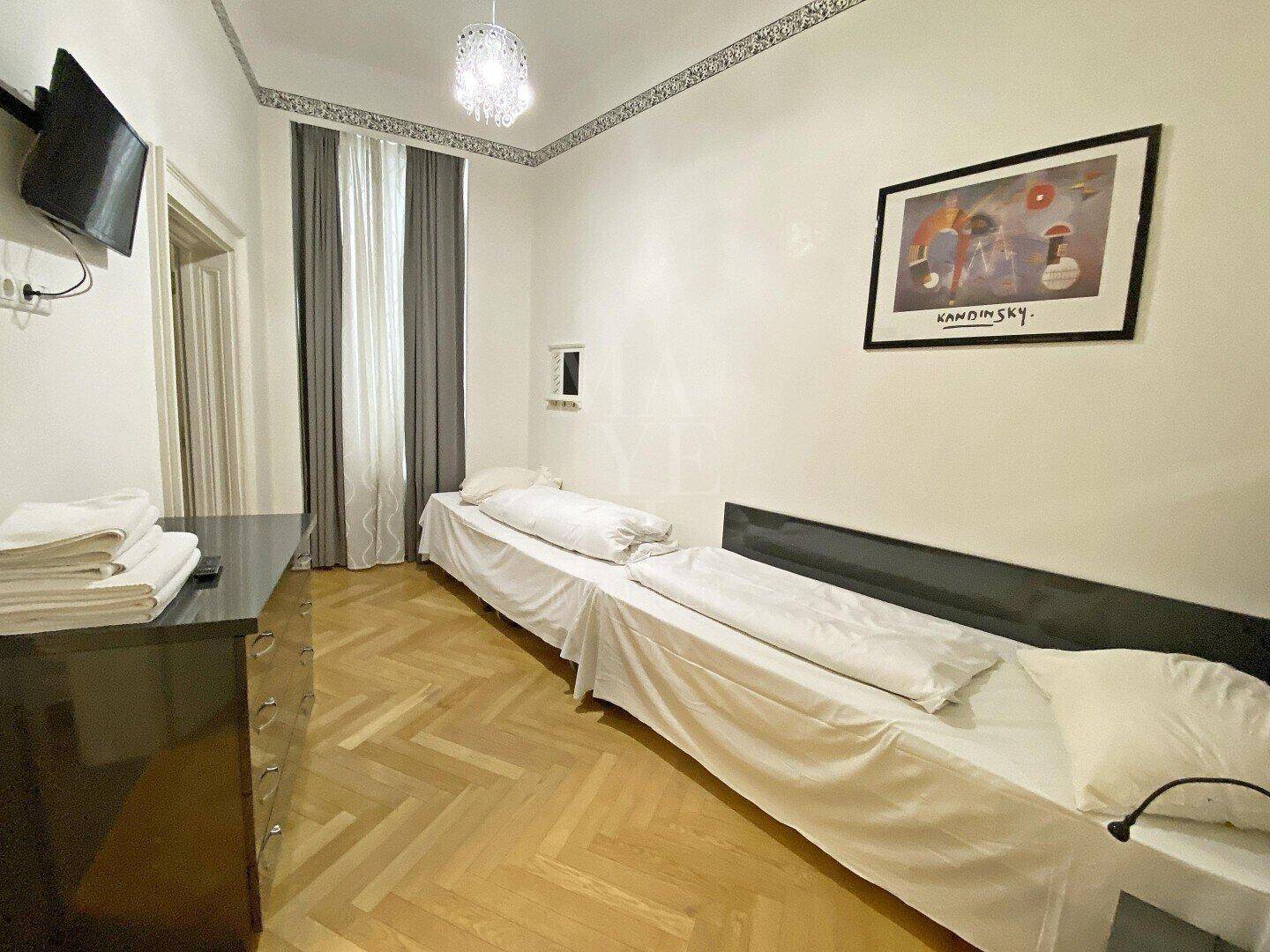 Schlafzimmer mit zwei Einzelbetten, Fischgrätparkett und moderner Dekoration.