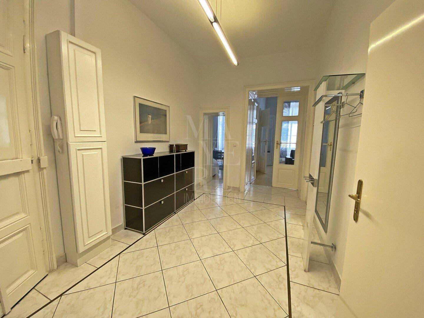 Heller Flur mit Fliesenboden, modernem Sideboard und Garderobe.