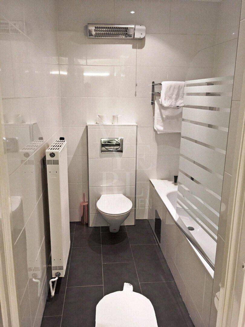 Modernes Badezimmer mit Badewanne, Toilette und weißen Wandfliesen.