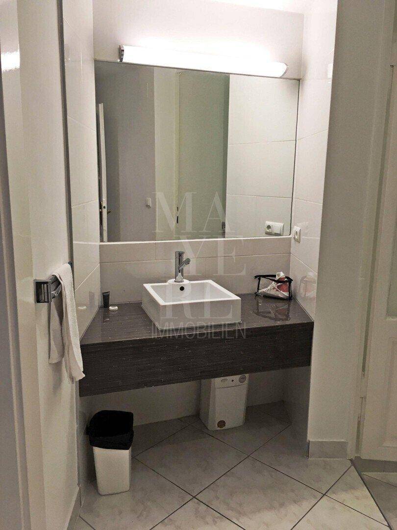 Badezimmer mit modernem Aufsatzwaschbecken, großem Spiegel und dunkler Ablagefläche.