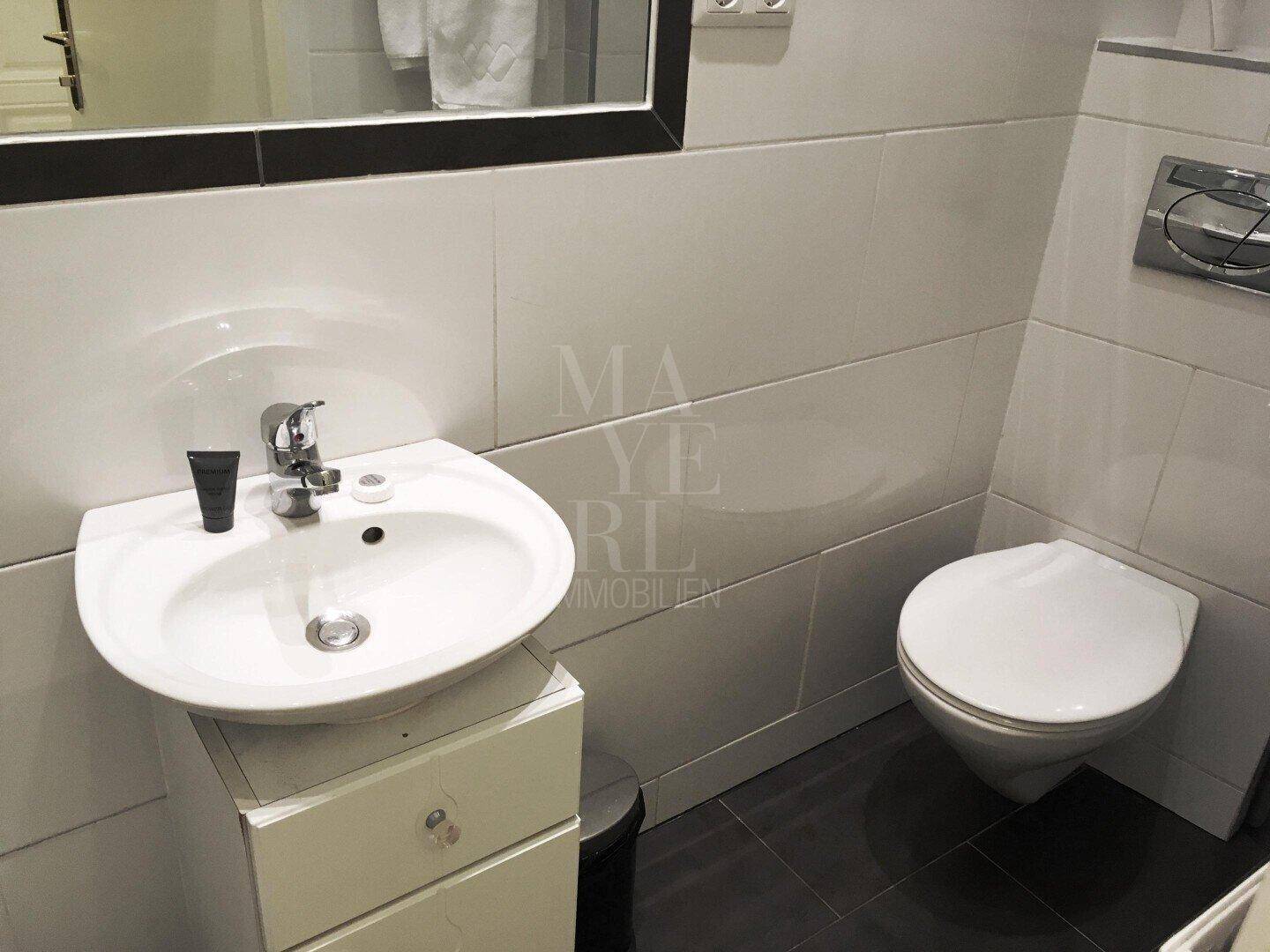 Separates WC mit Waschbecken und wandhängender Toilette.