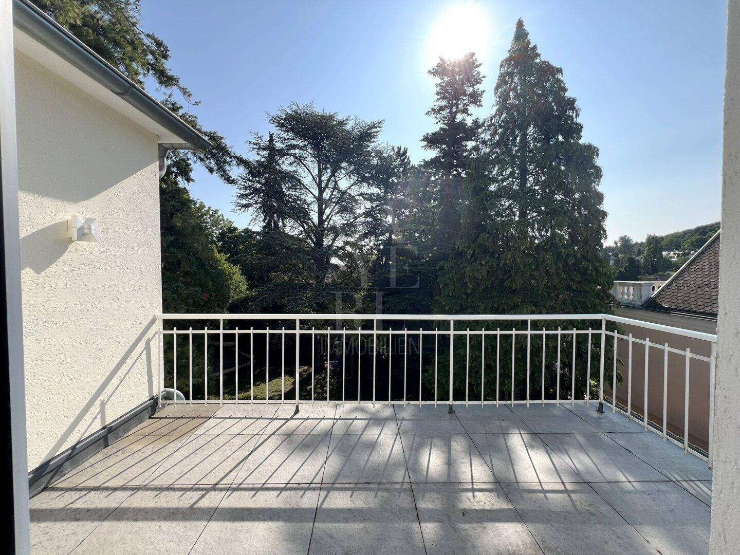 Großer sonniger Balkon mit Fliesenboden und Blick ins Grüne, ideal zum Entspannen.