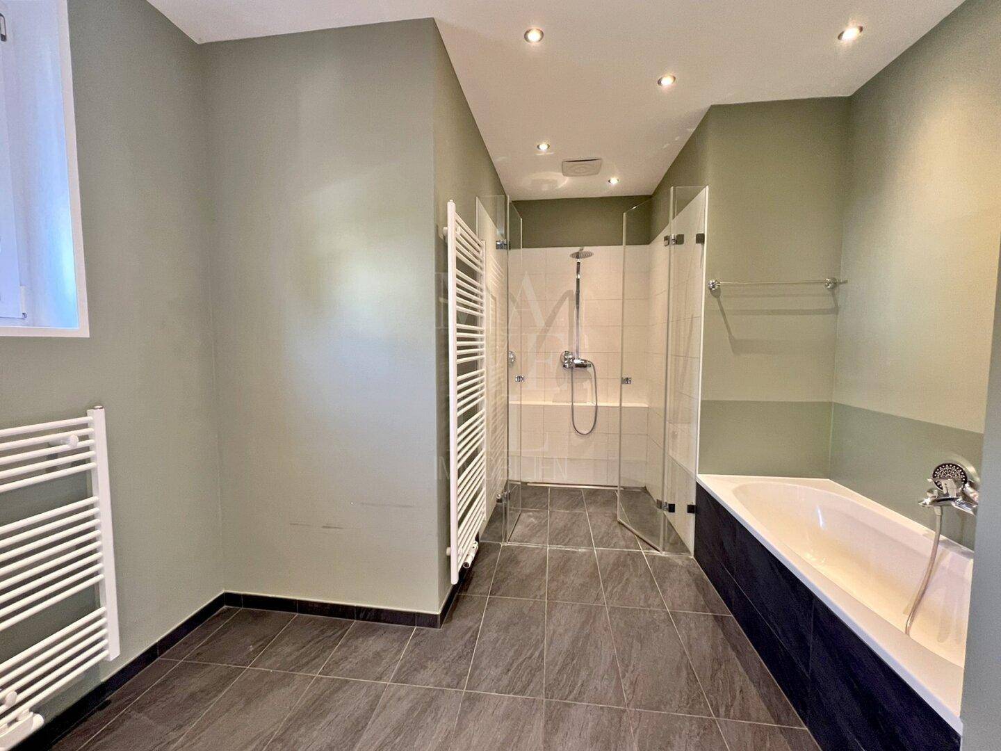Geräumiges Badezimmer mit Dusche, Badewanne und modernem Handtuchheizkörper.