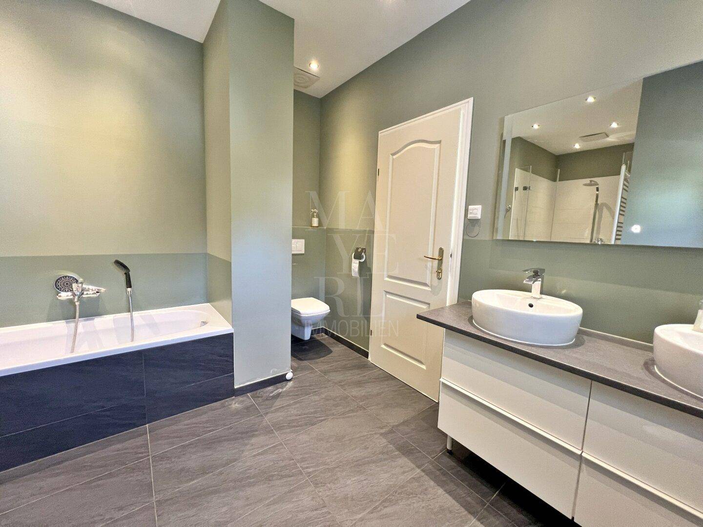 Modernes Badezimmer mit Doppelwaschbecken, Toilette und großem Spiegel.