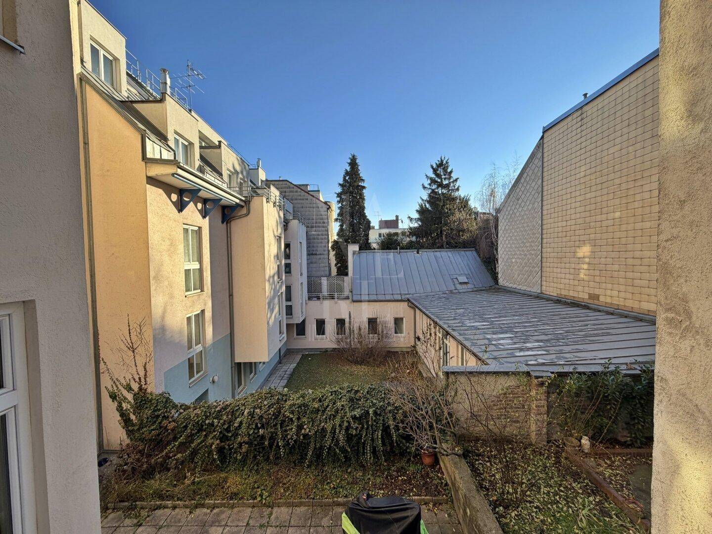 Blick auf den begrünten Innenhof eines Wohngebäudes mit verschiedenen Fassaden.