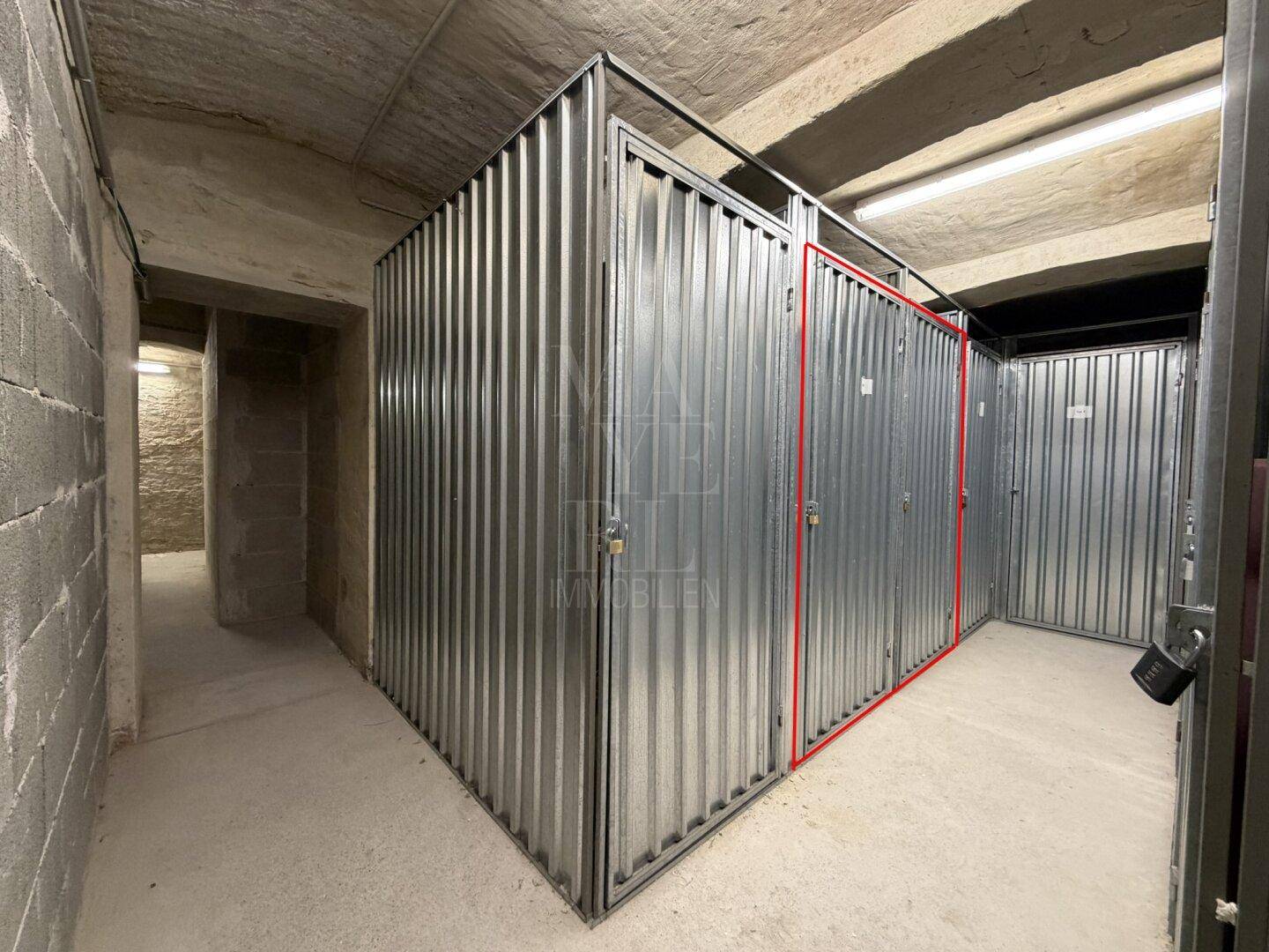 Kellerabteil mit Metallwänden und Betonboden, ideal für zusätzlichen Stauraum.