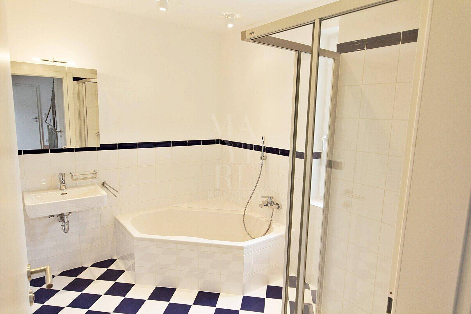 Modernes Badezimmer mit Eckbadewanne, Dusche und auffälligem schwarz-weiß kariertem Fliesenboden.