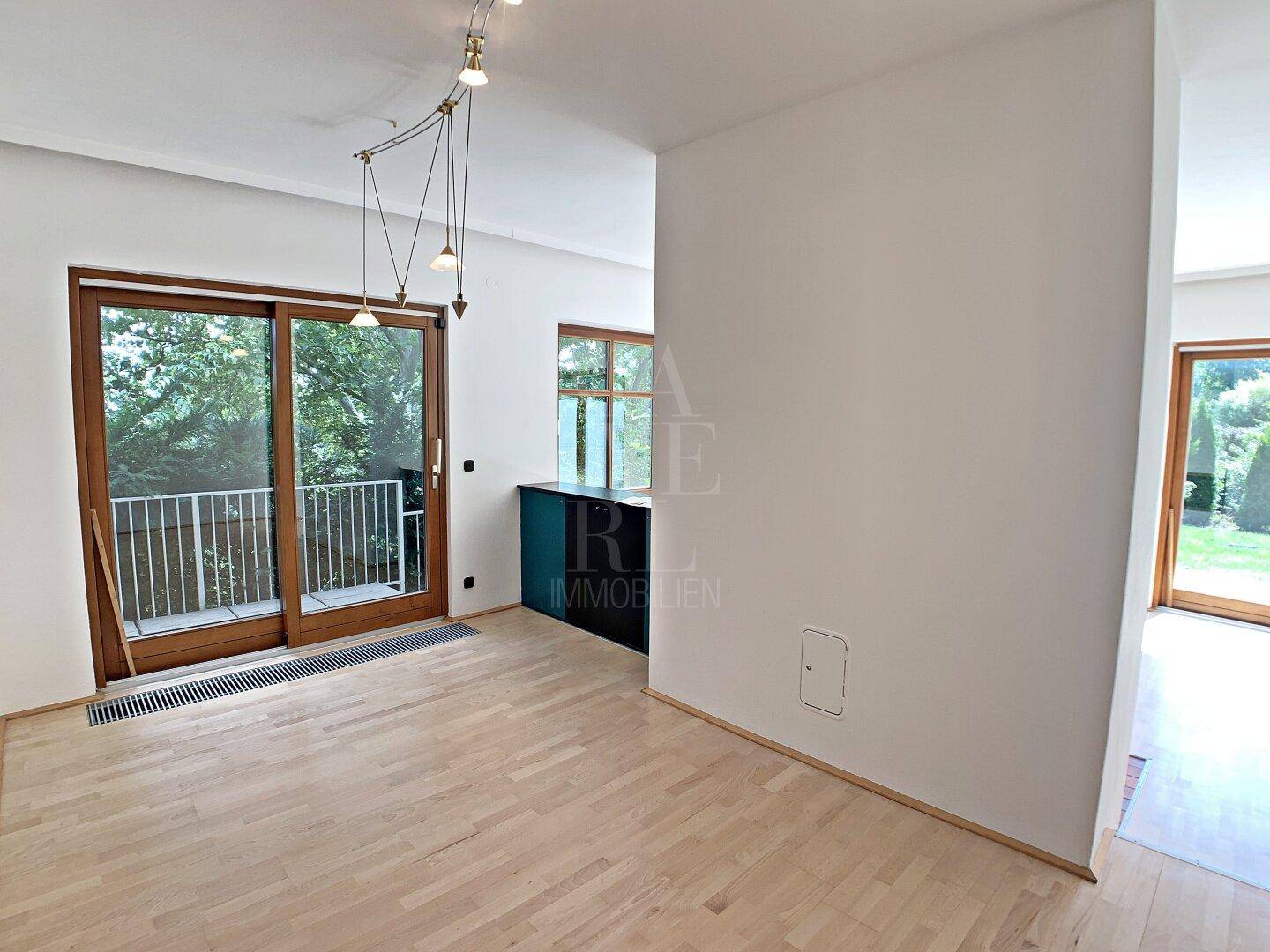 Offener Bereich mit Parkettboden und Zugang zu einem Balkon, ideal für einen Essbereich.