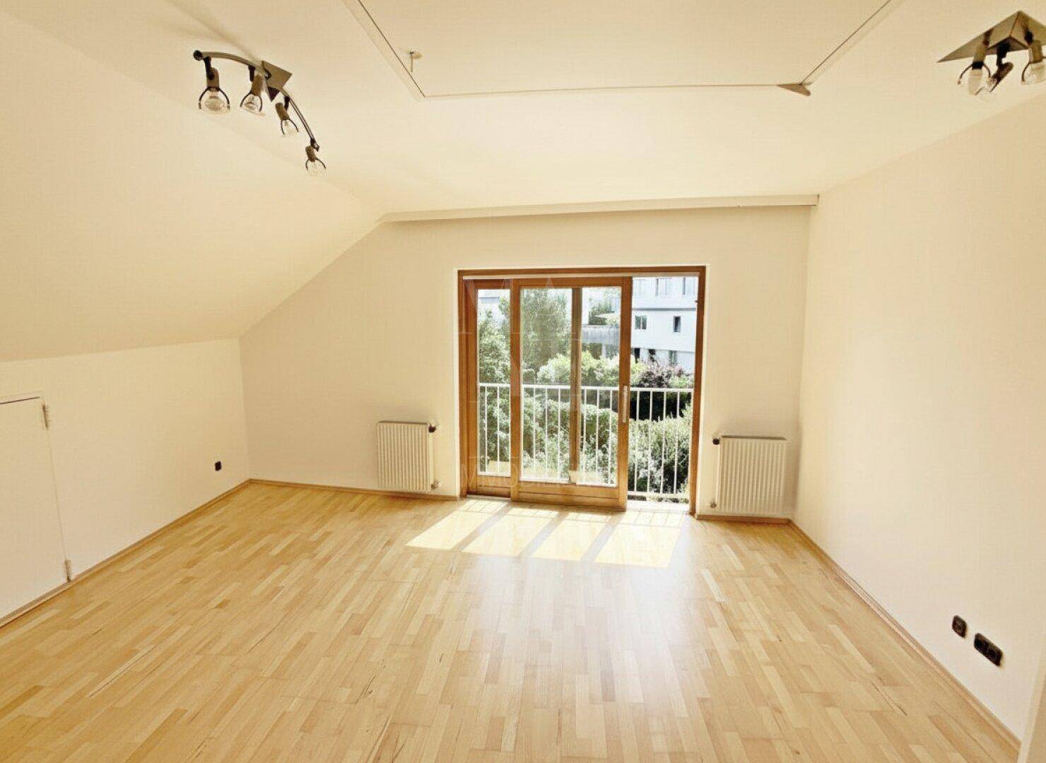 Geräumiger Dachbodenraum mit Parkettboden und französischem Balkon, der viel Licht spendet.
