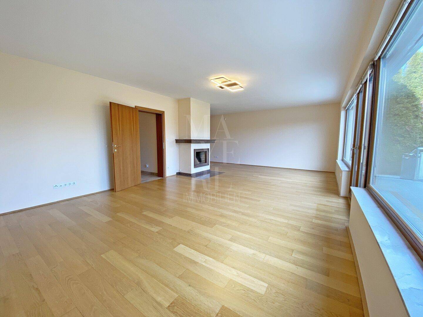Helles Wohnzimmer mit Kamin und Parkettboden, bietet eine gemütliche Atmosphäre.