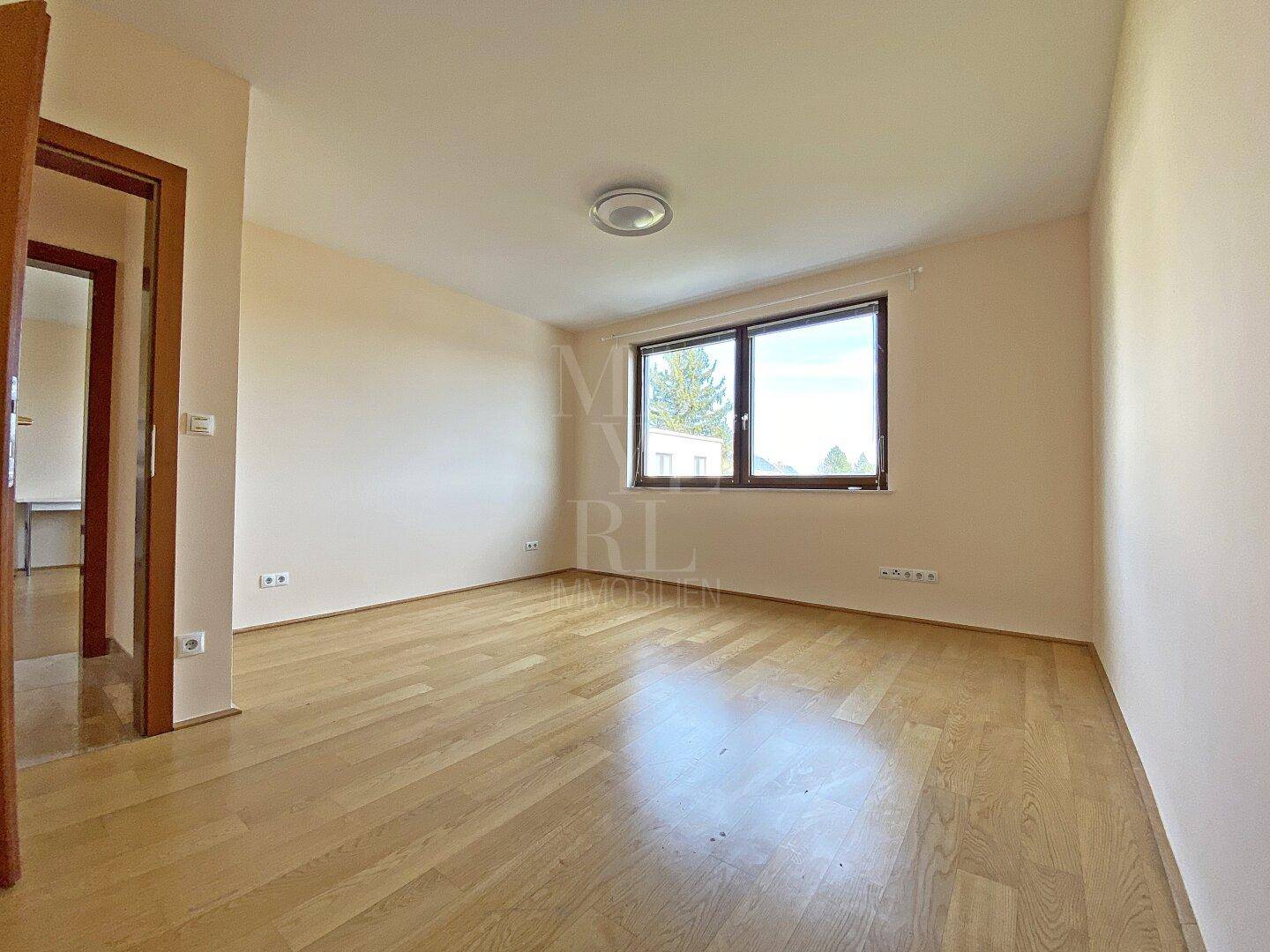 Leeres Schlafzimmer mit Parkettboden und Fenster, bietet viel Potenzial für persönliche Einrichtung.