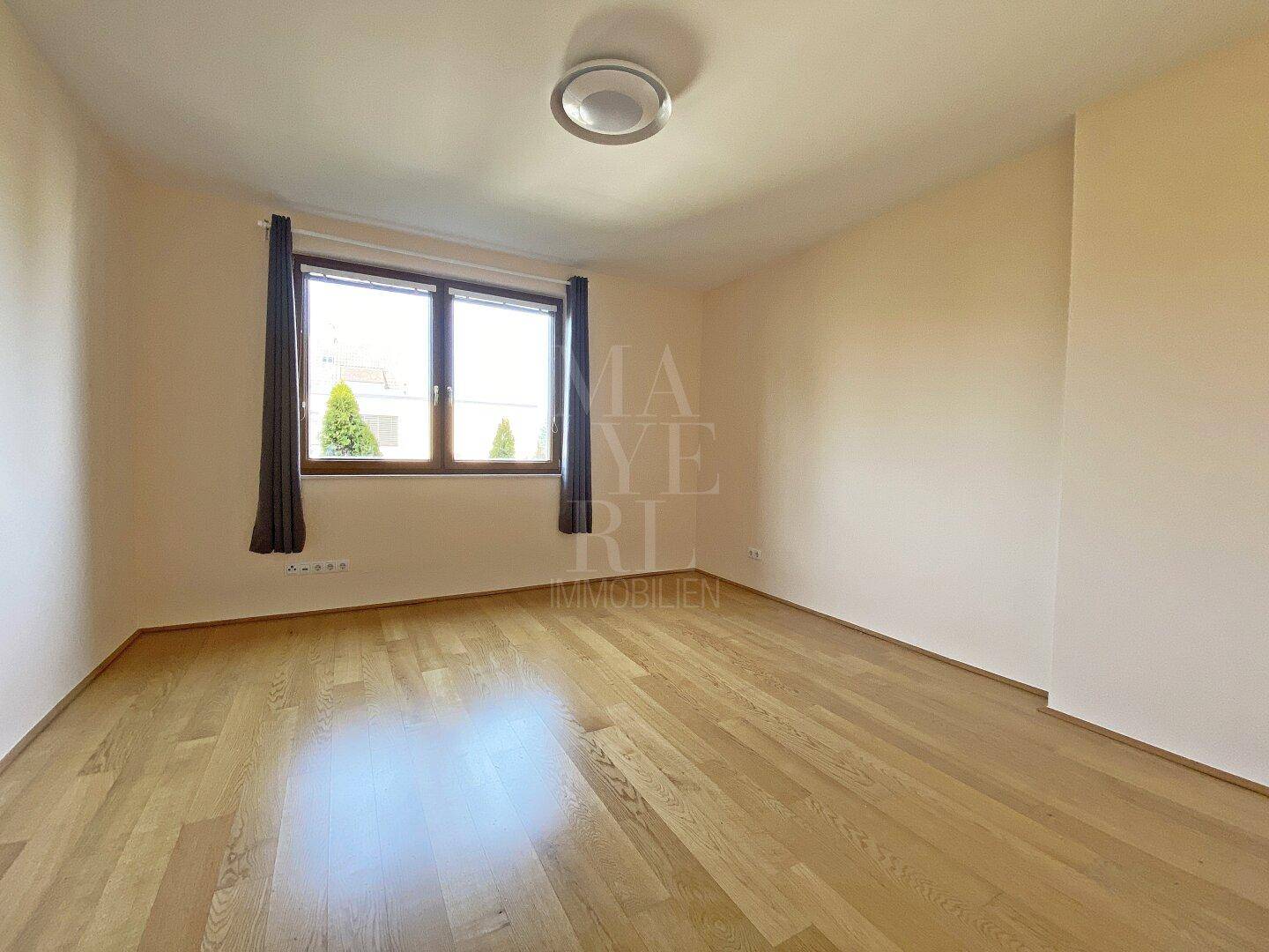 Helles Schlafzimmer mit Parkettboden und Fenster, bietet eine angenehme Wohnatmosphäre.