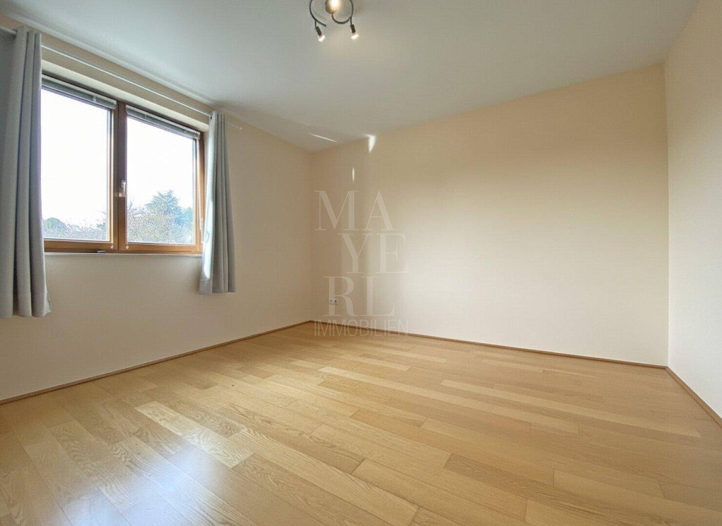 Leeres Schlafzimmer mit hellem Parkettboden und Fenster, bereit zur individuellen Gestaltung.