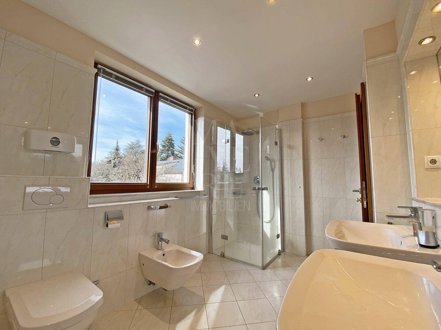 Modernes Badezimmer mit Duschkabine, Bidet, WC und Fenster, hell und funktional gestaltet.