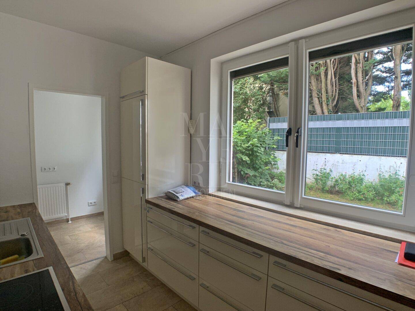 Helle Küche mit Fensterblick ins Grüne und praktischer Arbeitsfläche entlang der Wand.
