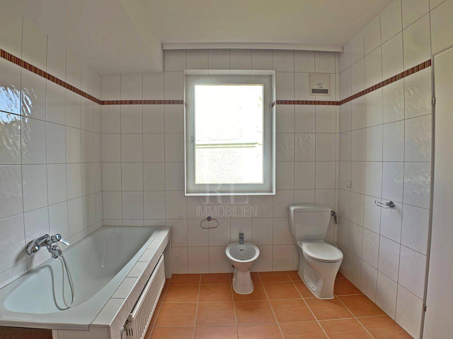 Klassisches Badezimmer mit Badewanne, Bidet, Toilette und Fenster für Tageslicht.
