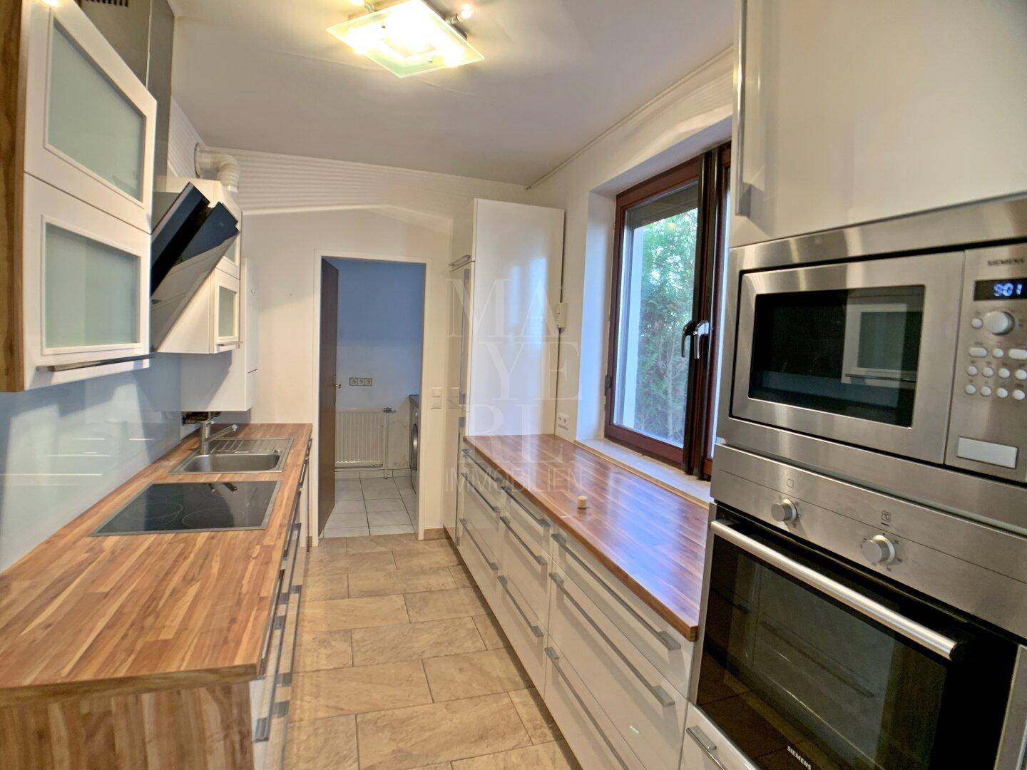 Funktionale Küche mit modernen Einbaugeräten, Mikrowelle, Backofen und Fenster.