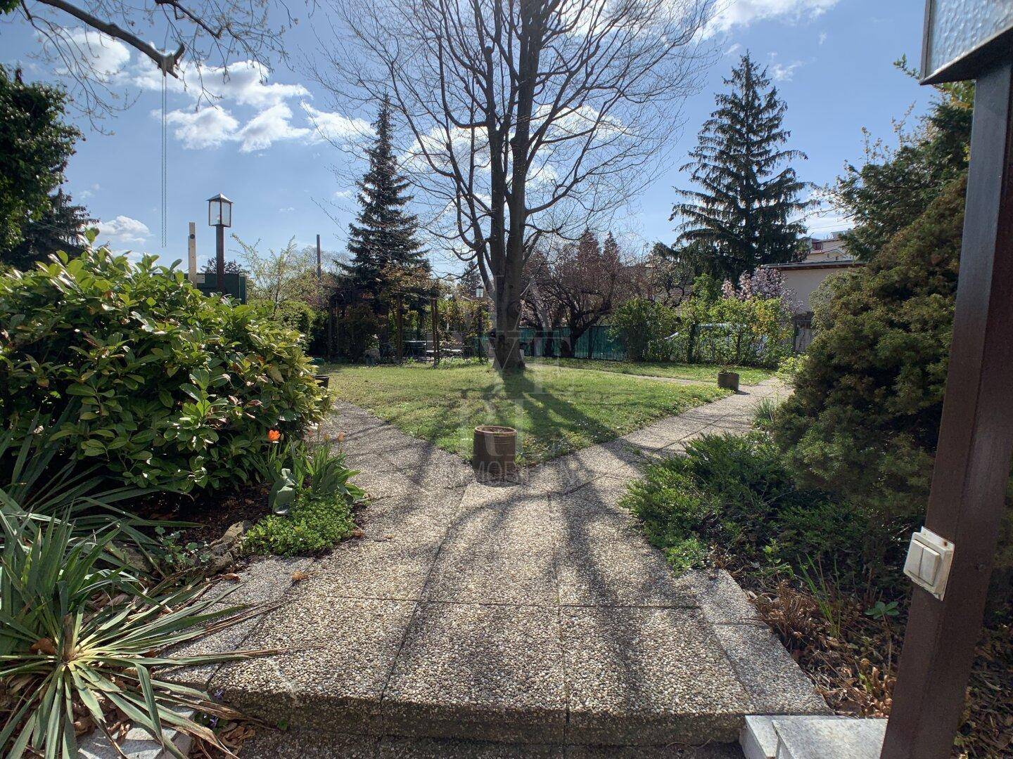 Gepflegter Garten mit altem Baumbestand, Rasenflächen und Steinwegen.