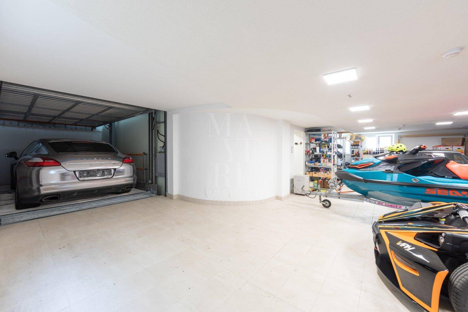 Geräumige Tiefgarage mit Parklift und Abstellmöglichkeiten für verschiedene Fahrzeuge und Sportgeräte.