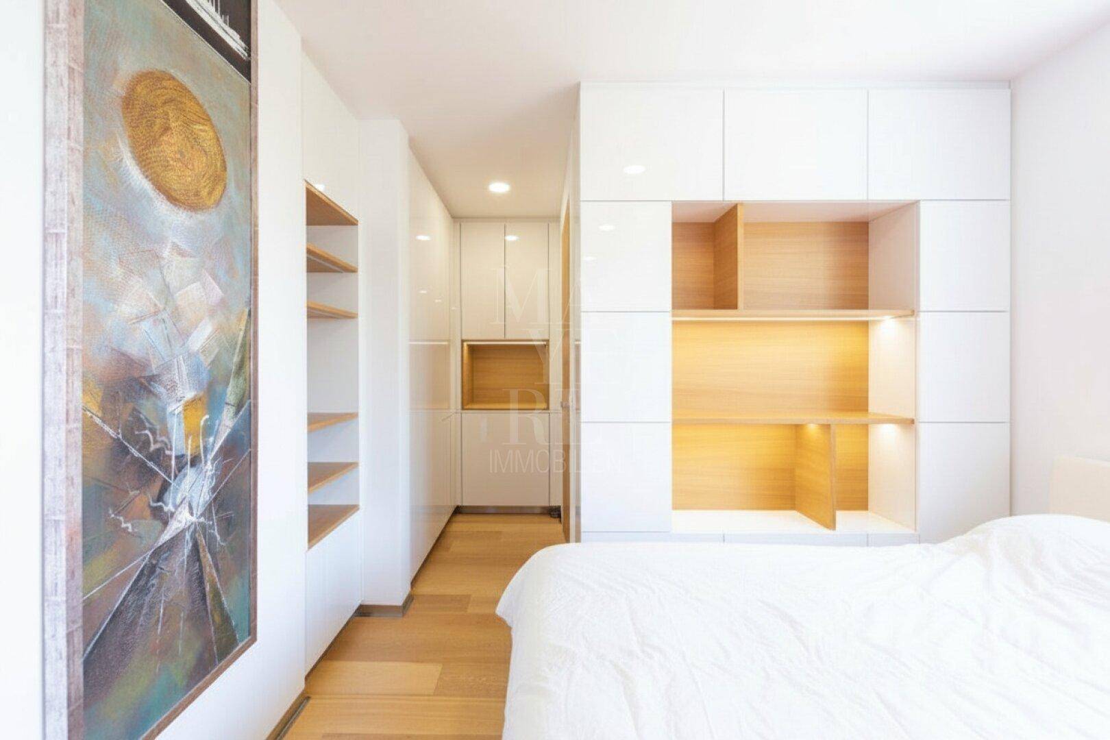 Schlafzimmer mit maßgefertigten Einbauschränken und Regalen, die viel Stauraum bieten.