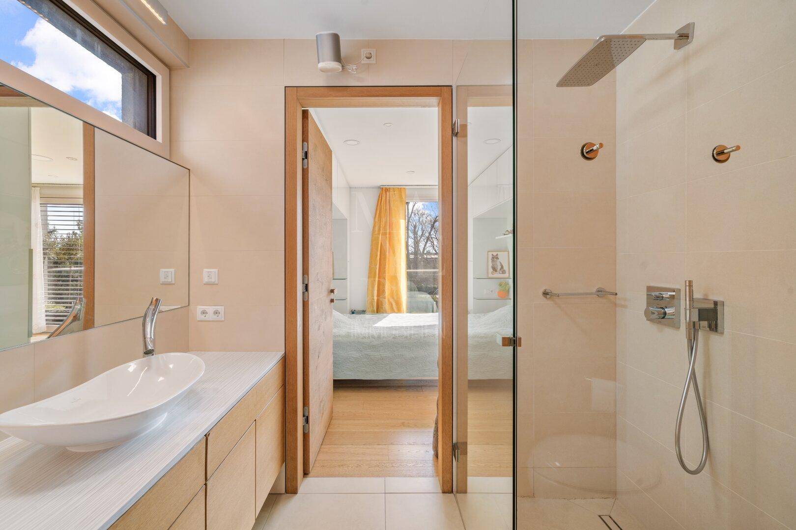 Modernes Ensuite-Badezimmer mit Regendusche, Einzelwaschbecken und Zugang zum Schlafzimmer.