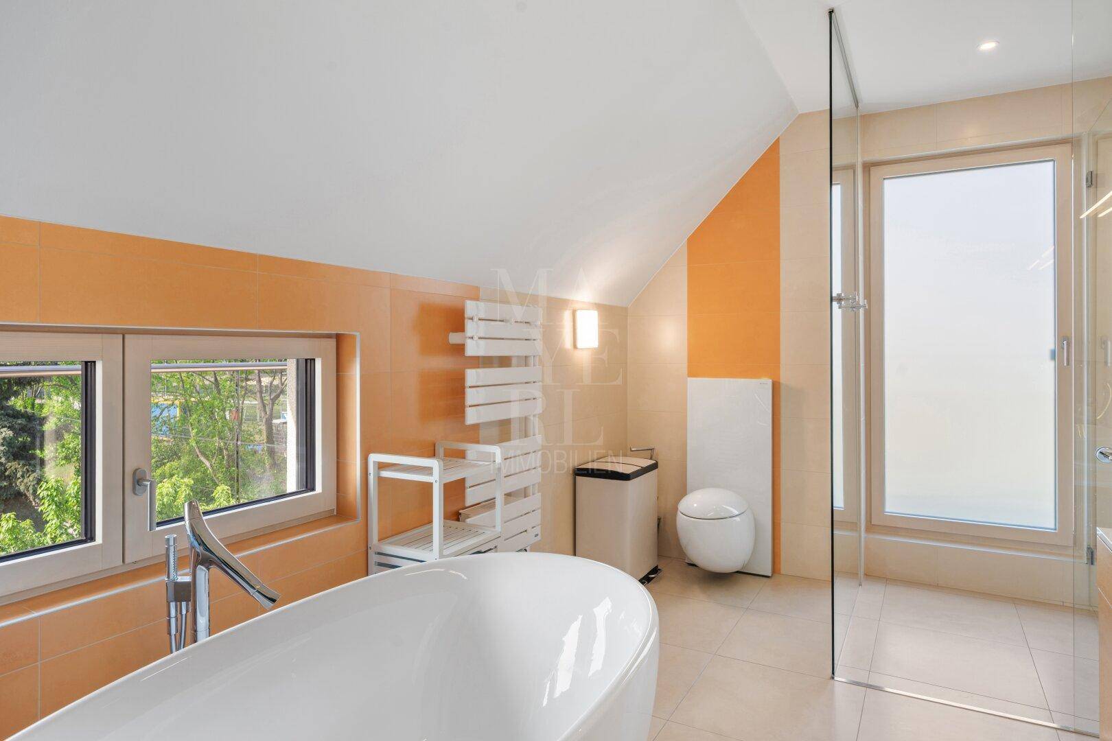 Modernes Badezimmer mit freistehender Badewanne, Dusche und beheiztem Handtuchhalter unter Dachschrägen.