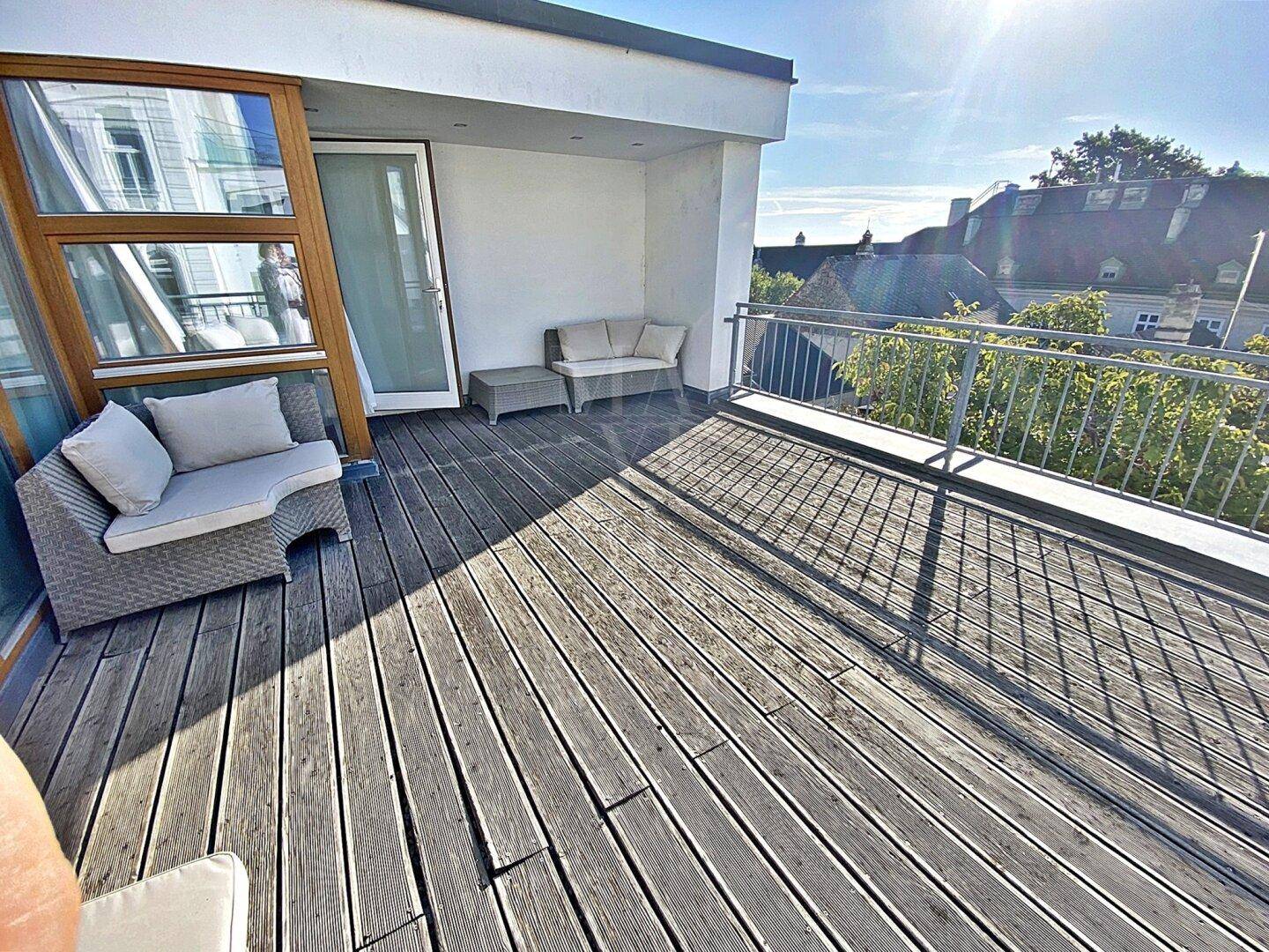 Geräumiger Balkon mit Holzbelag und bequemen Outdoor-Möbeln, mit Stadtblick.