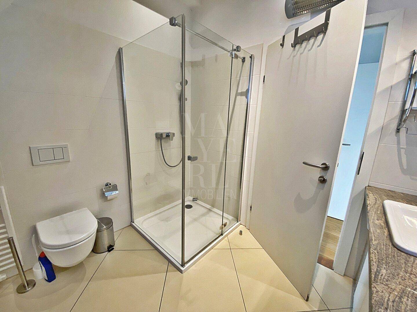 Helles Badezimmer mit moderner Duschkabine und wandhängendem WC.