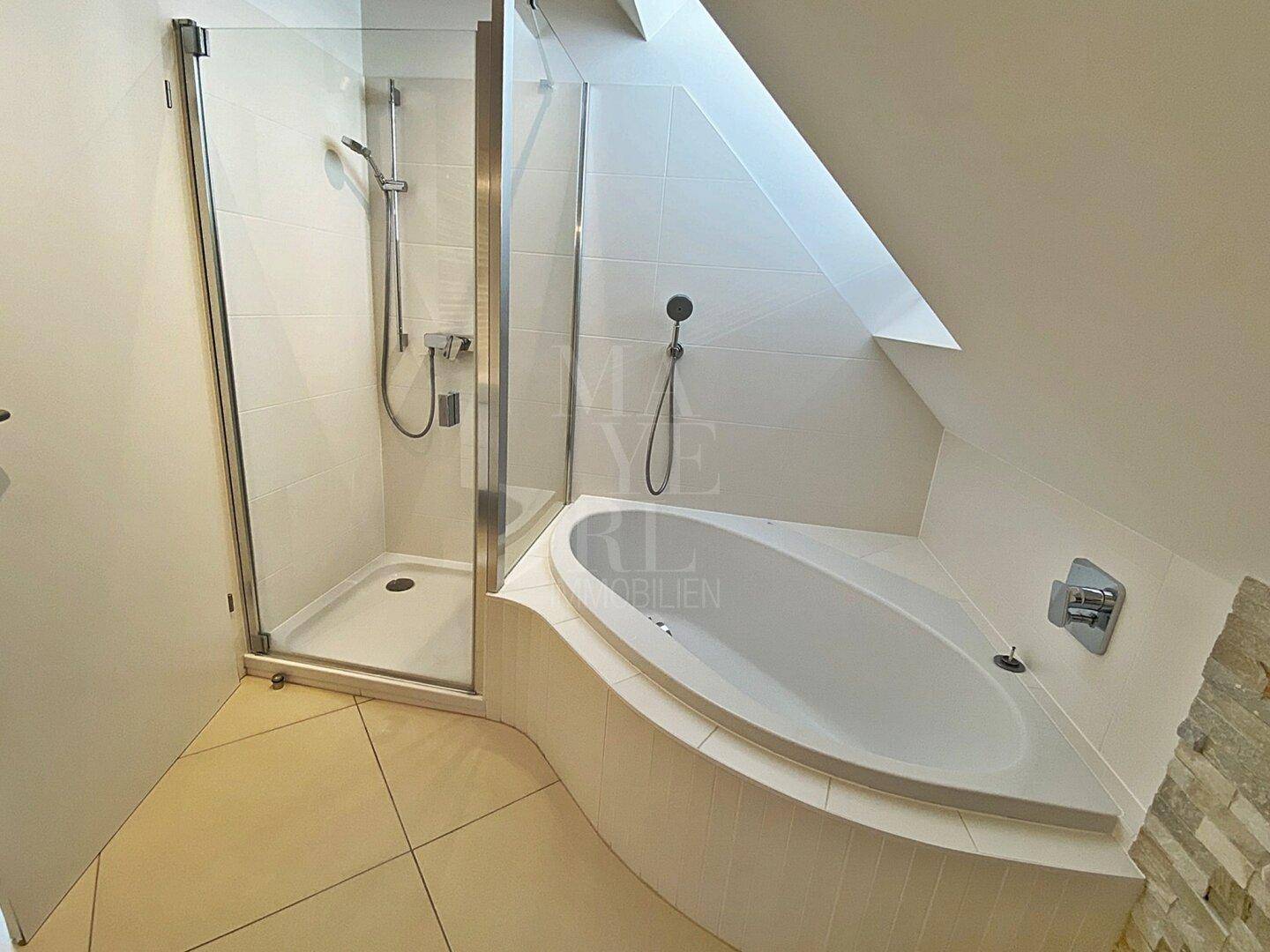 Geräumiges Badezimmer mit Eckbadewanne und separater Duschkabine unter Dachschräge.