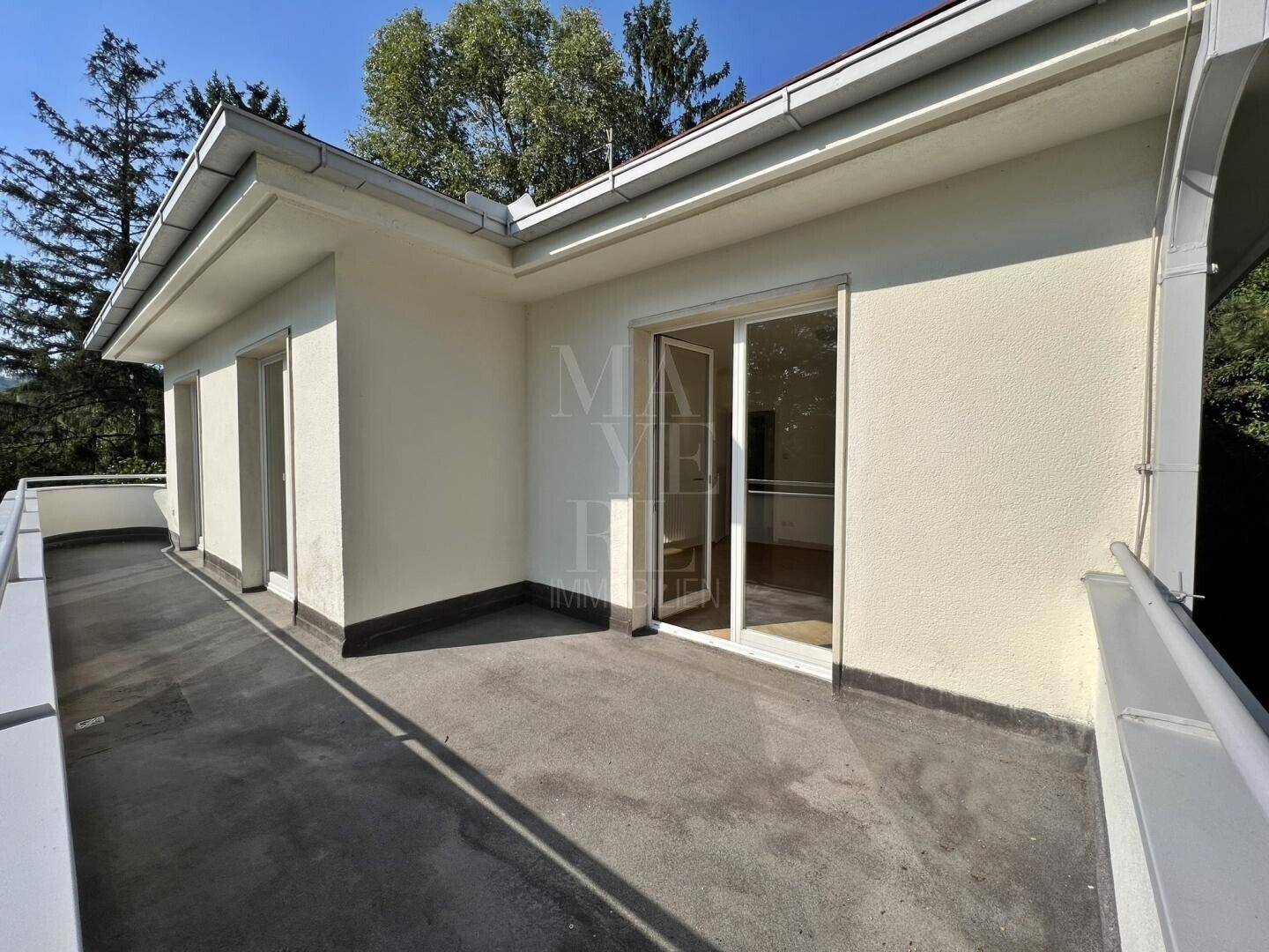 Geräumige Terrasse mit Betonboden und Schiebetüren, die den Zugang zum Innenbereich ermöglichen.