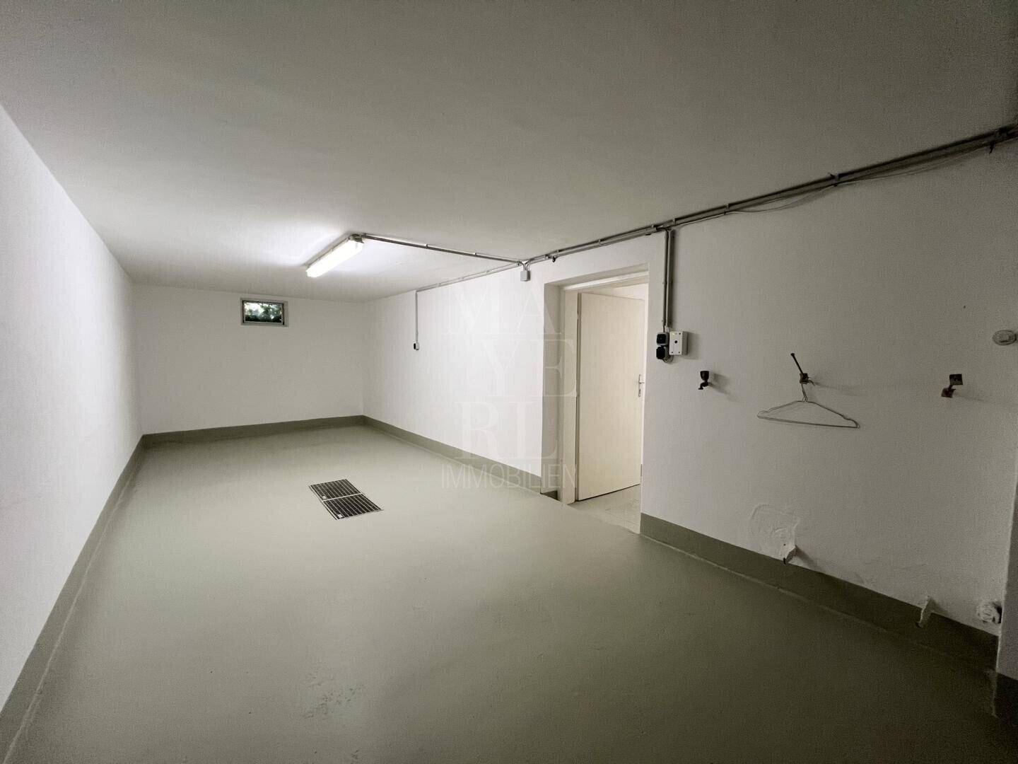 Geräumiger, leerer Raum im Untergeschoss mit Betonboden und kleinem Fenster.