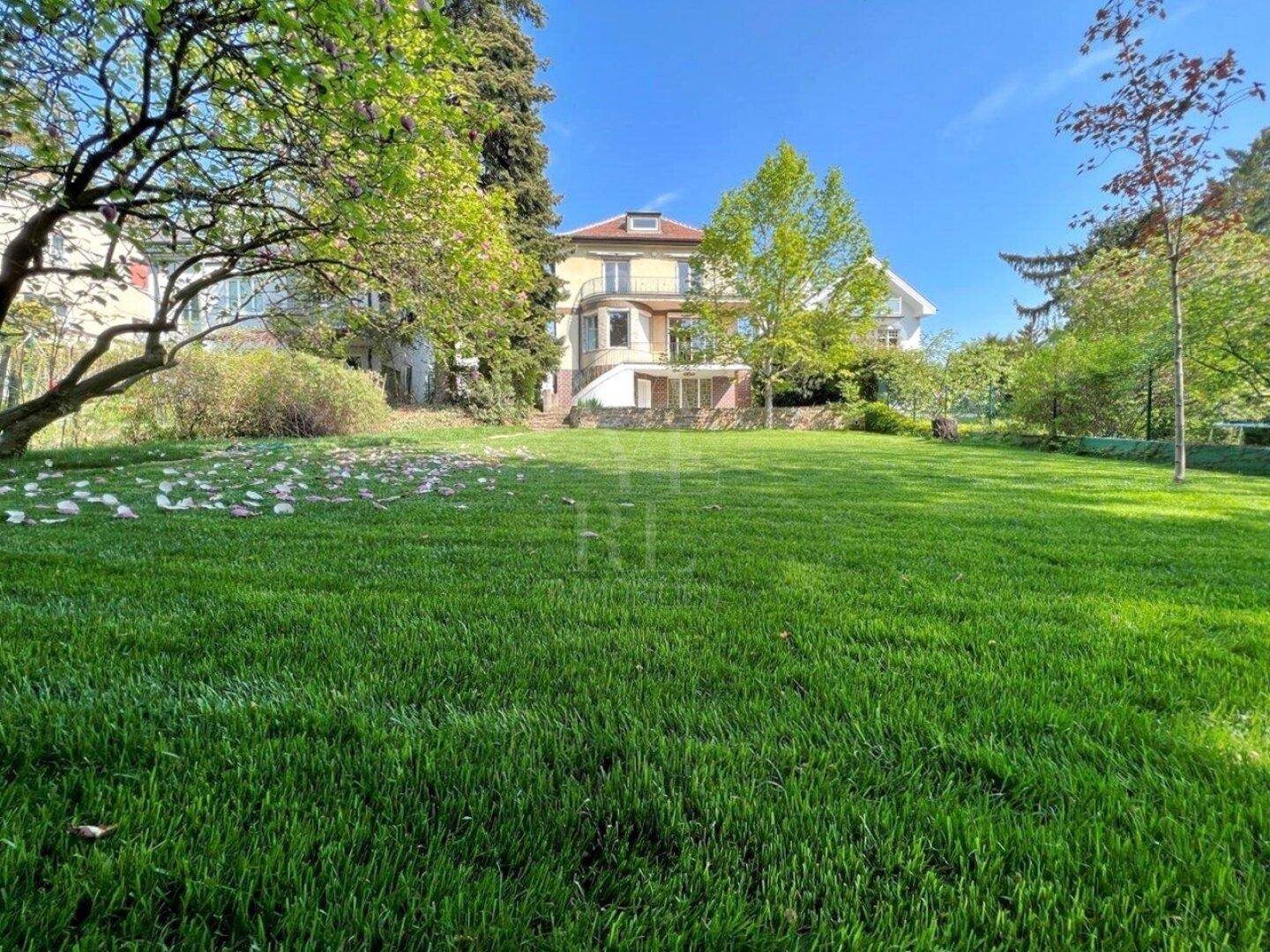 Weitläufiger Garten mit gepflegtem Rasen und altem Baumbestand, der das Haus umgibt.