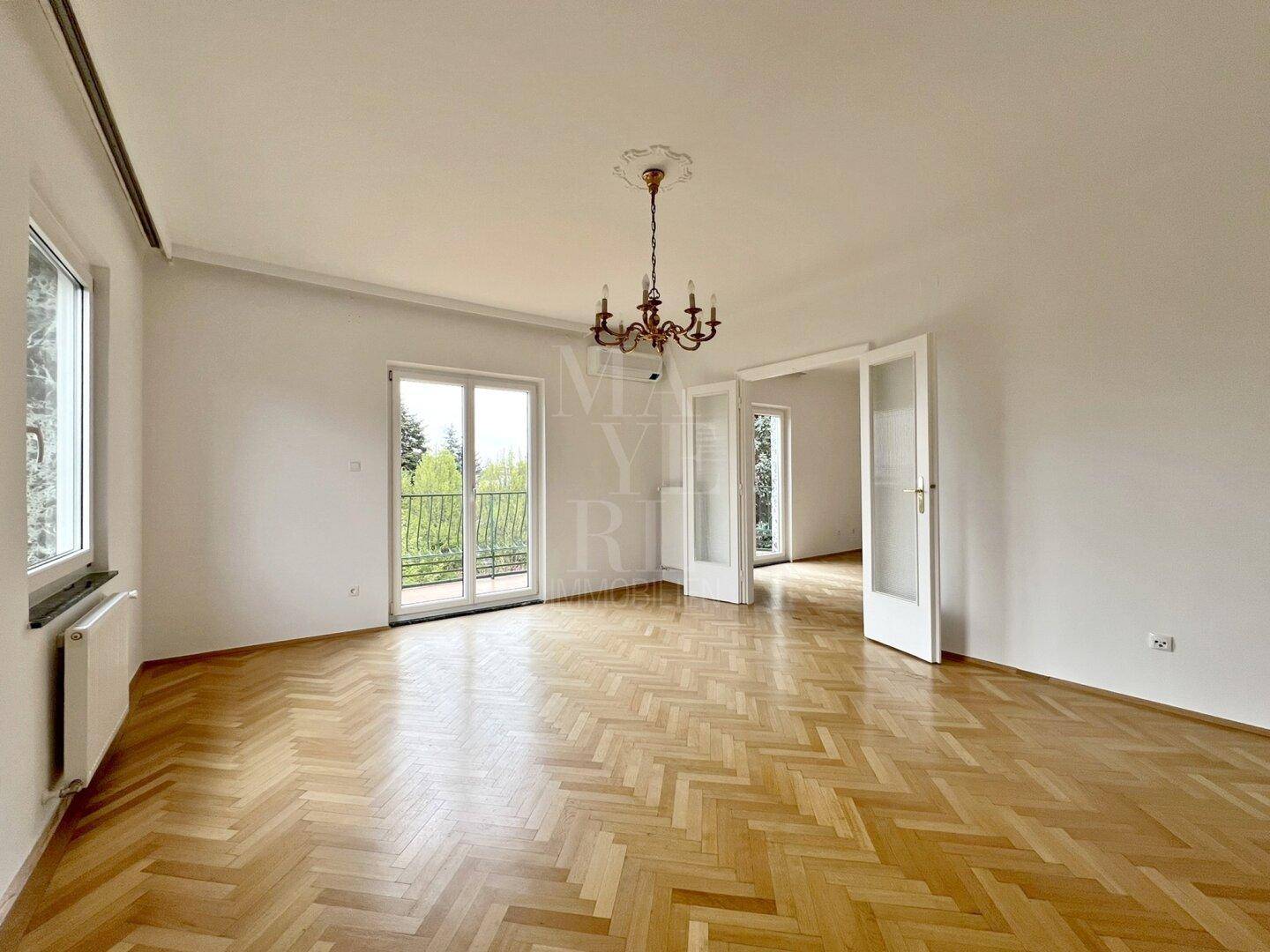 Großes Schlafzimmer mit klassischem Fischgrätparkett, Klimaanlage und Zugang zu einem Balkon.