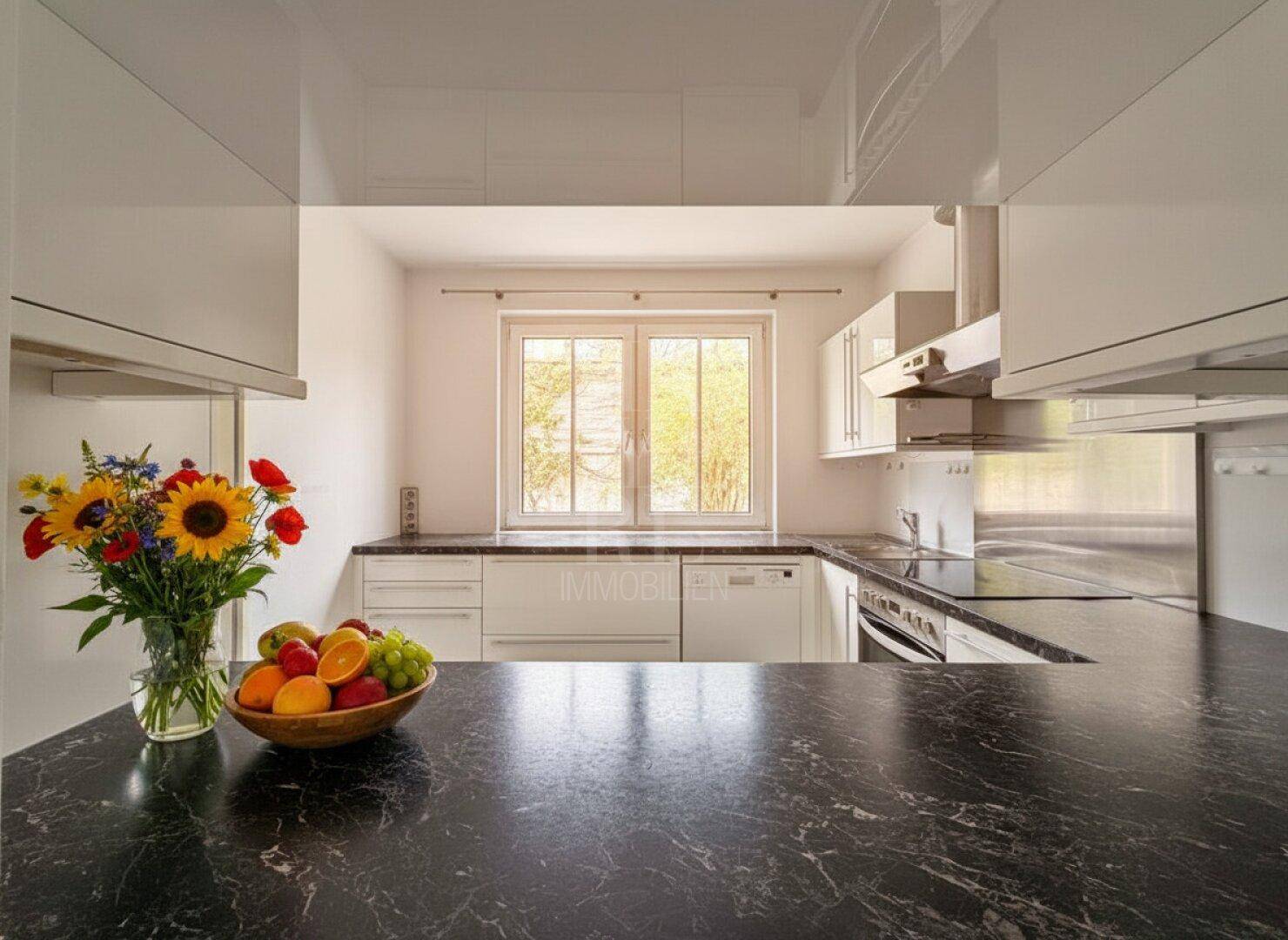 Küchenarbeitsplatte mit frischen Früchten und Blumen, Blick auf das Fenster und die Umgebung.