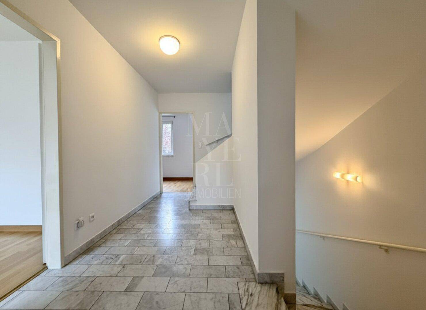 Heller Flur mit Marmorfliesenboden und einer eleganten Treppe, die in die oberen Stockwerke führt.