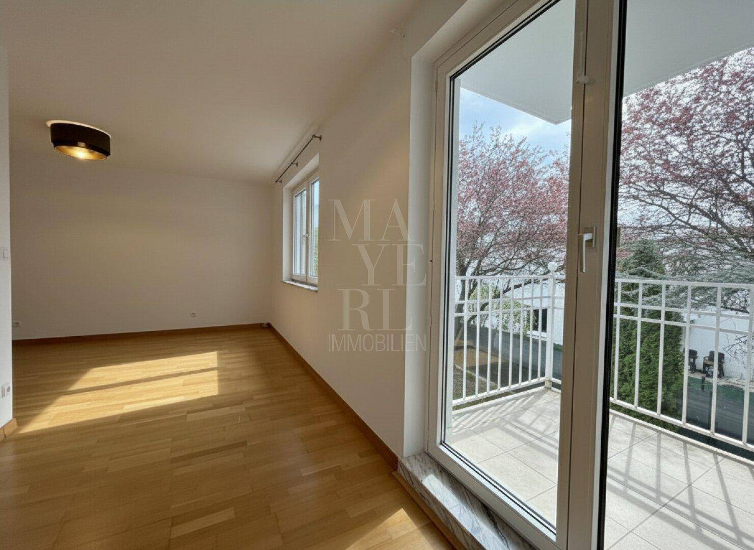 Geräumiges Schlafzimmer mit Holzfußboden und direktem Zugang zu einem privaten Balkon.