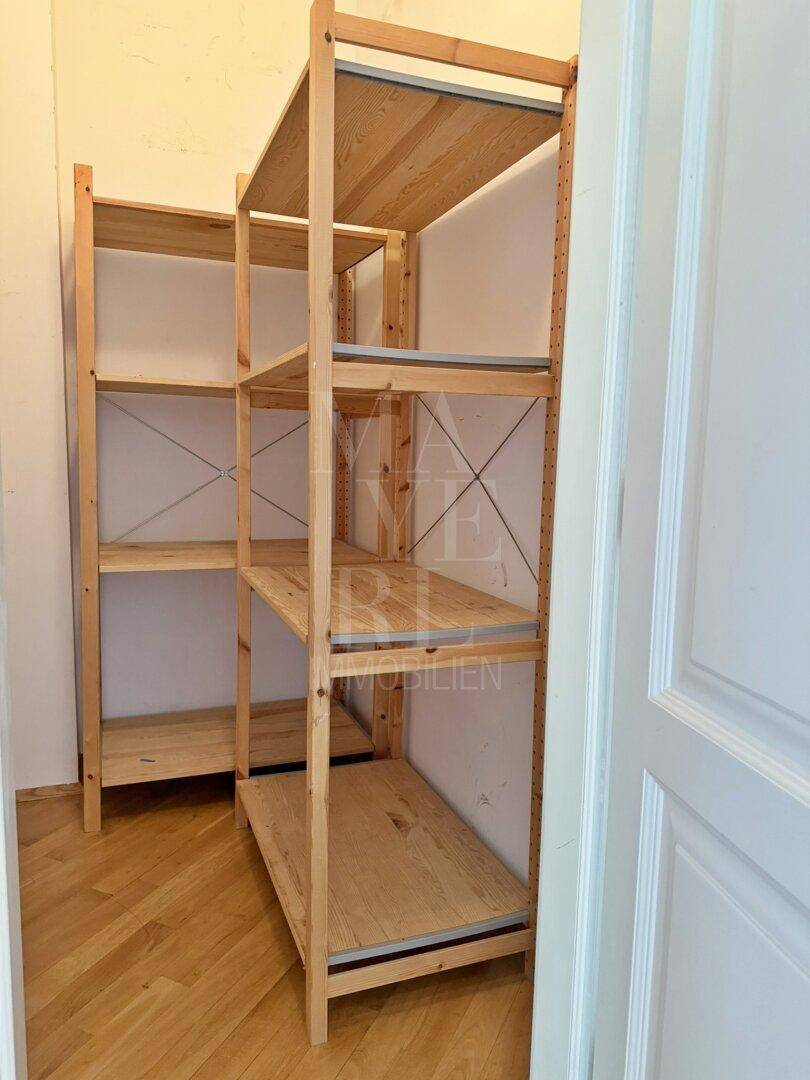 Praktischer Abstellraum mit offenen Holzregalen für zusätzlichen Stauraum und Organisation.