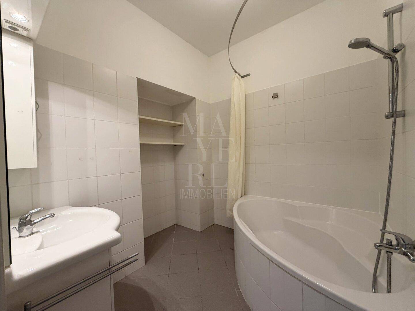 Badezimmer mit Badewanne, Waschbecken und weißen Fliesen, funktional und hell gestaltet.