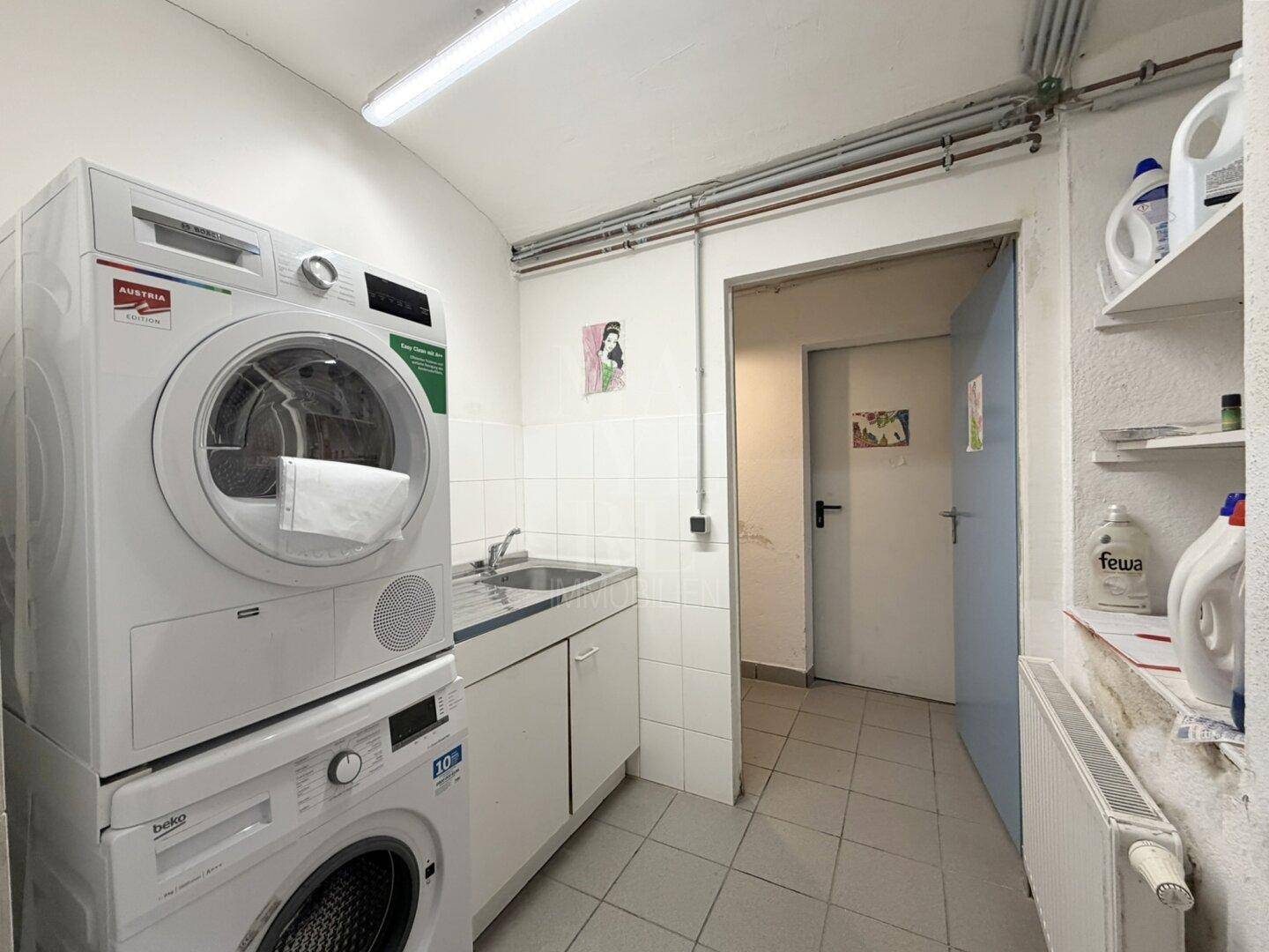 Gemeinschaftlicher Waschraum mit Waschmaschine, Trockner und Waschbecken, praktisch ausgestattet.