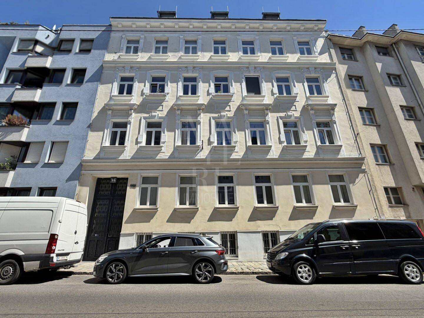 Historische Fassade eines Wohngebäudes mit vielen Fenstern und architektonischen Details.