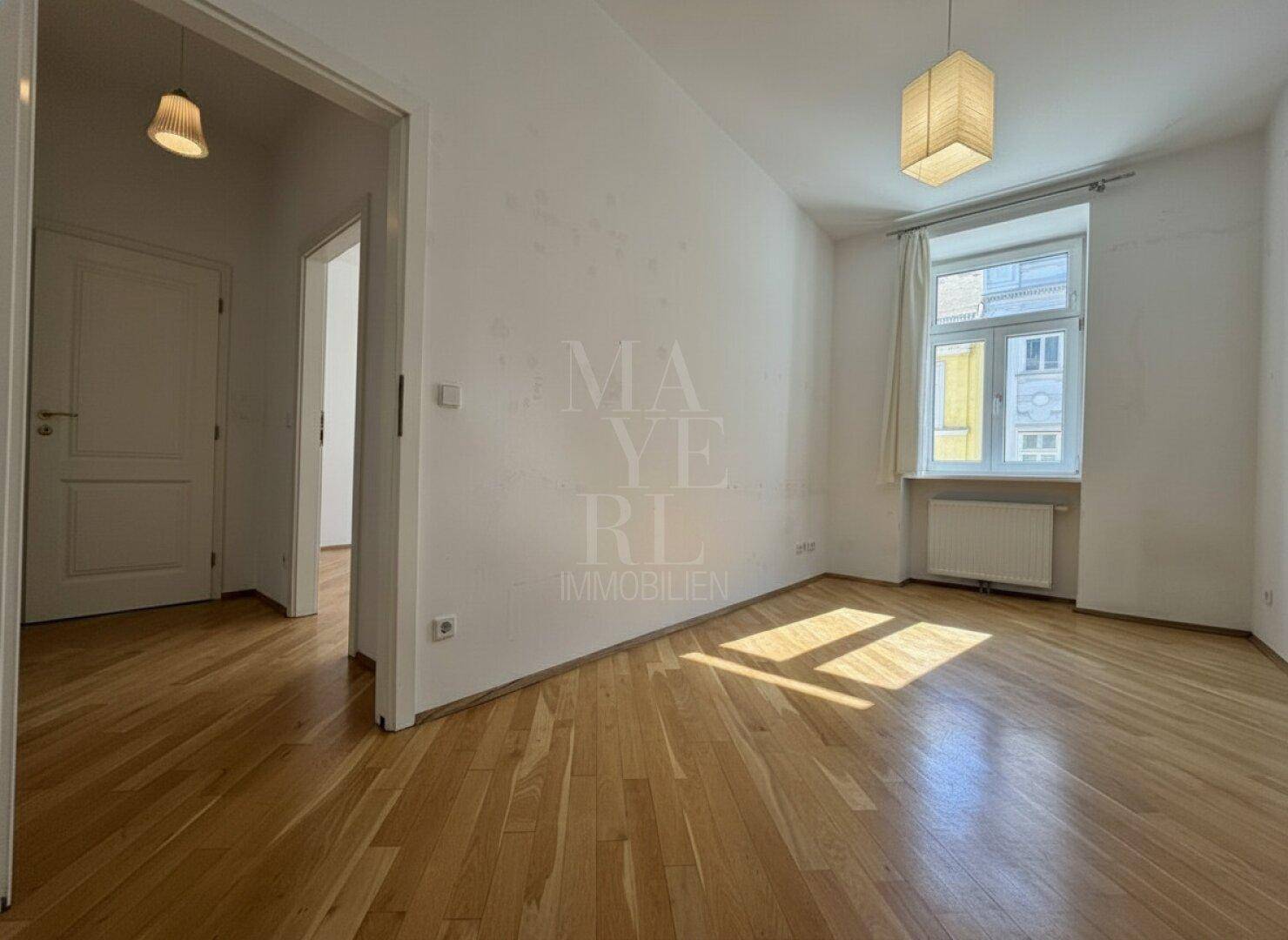 Geräumiges Schlafzimmer mit Parkettboden und einem Fenster, das den Raum mit Licht füllt.