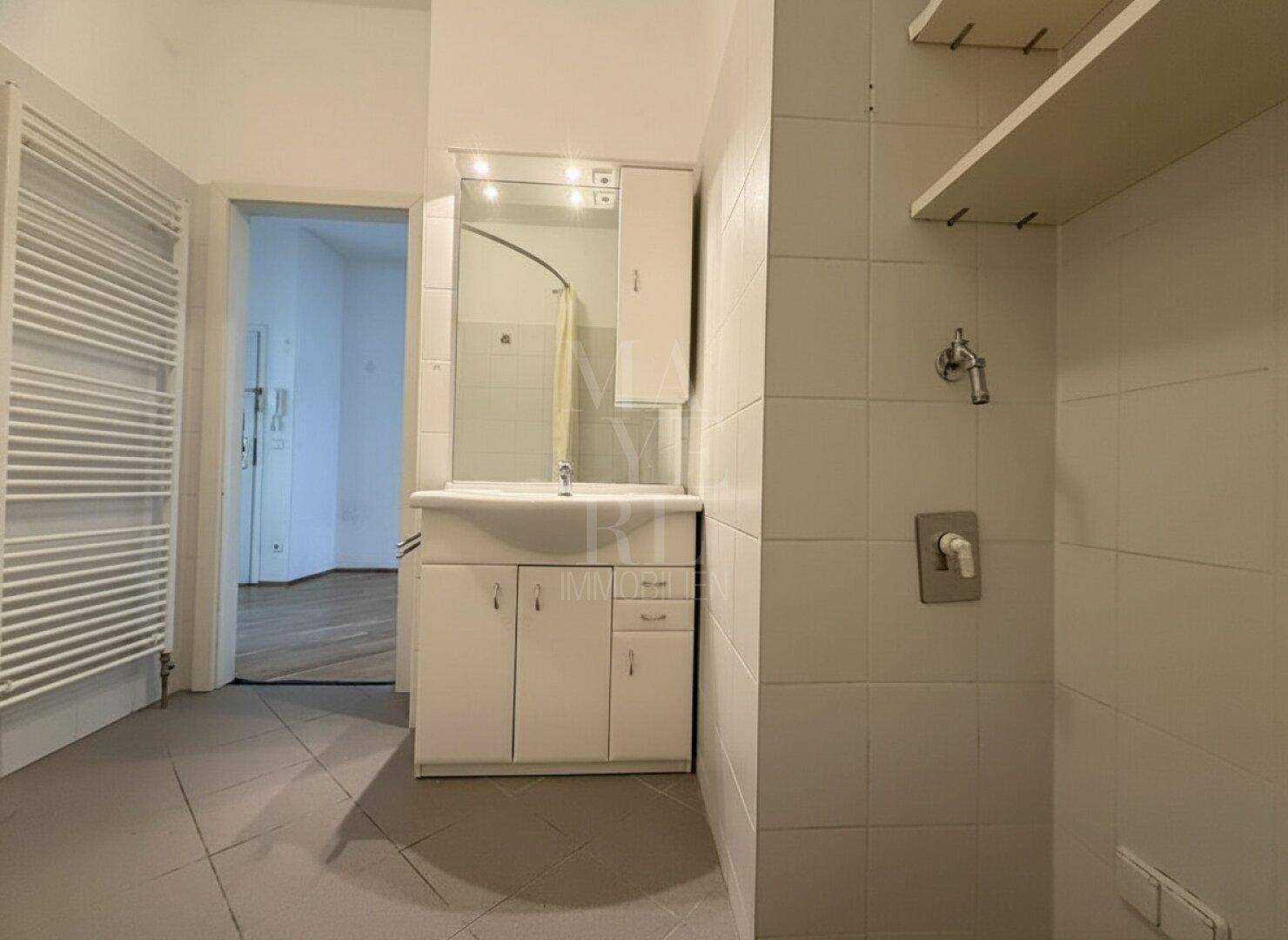 Badezimmer mit Waschbecken, Spiegelschrank und beheiztem Handtuchhalter, praktisch eingerichtet.