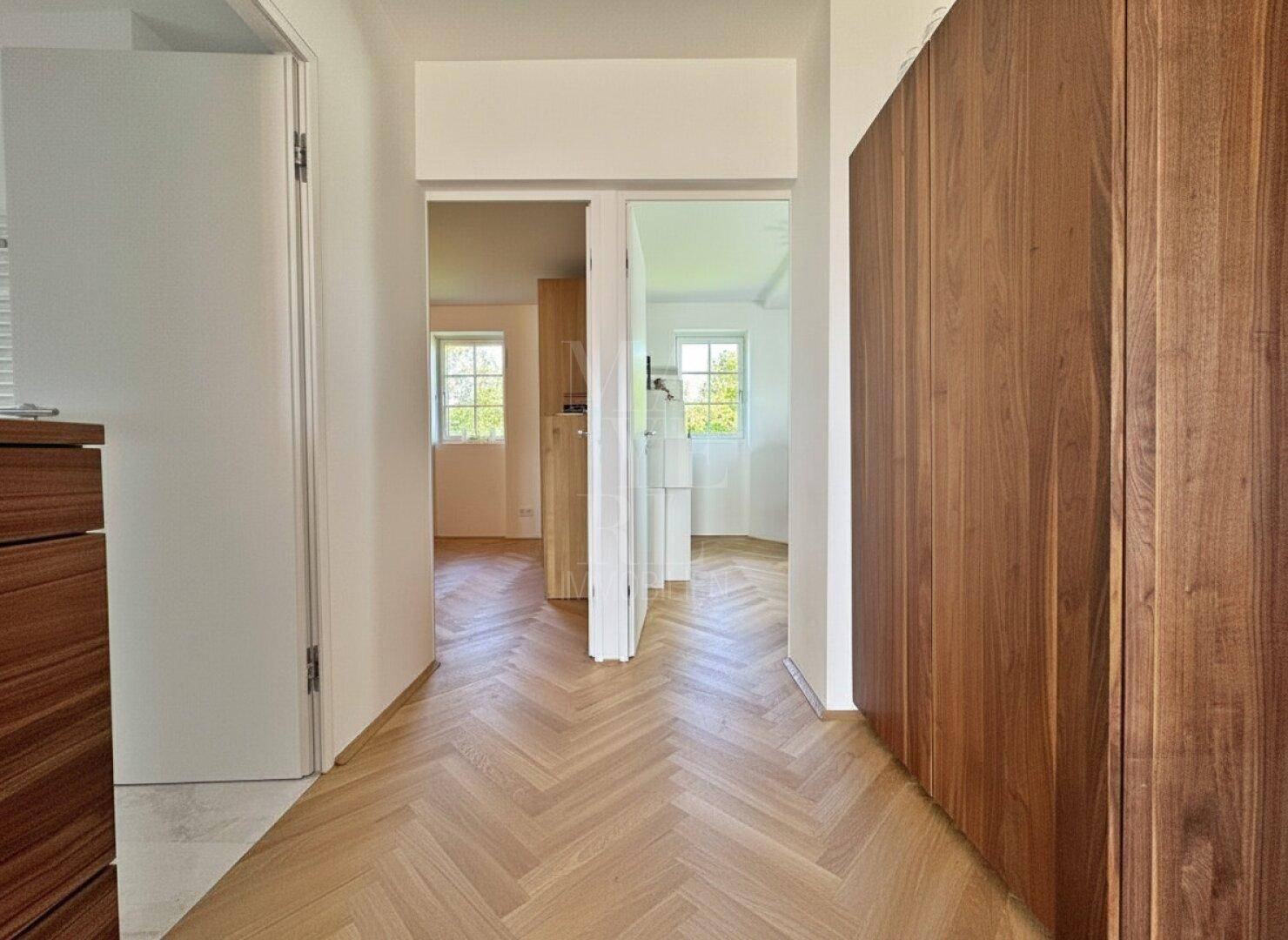 Moderner Flur mit Fischgrätparkett und einer eleganten Holzwandverkleidung.