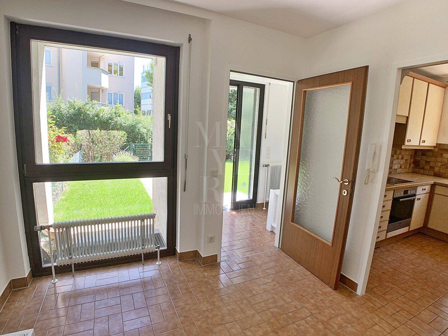 Essbereich in der Küche mit Fliesenboden und Blick auf den Garten, angrenzend an die Küche.