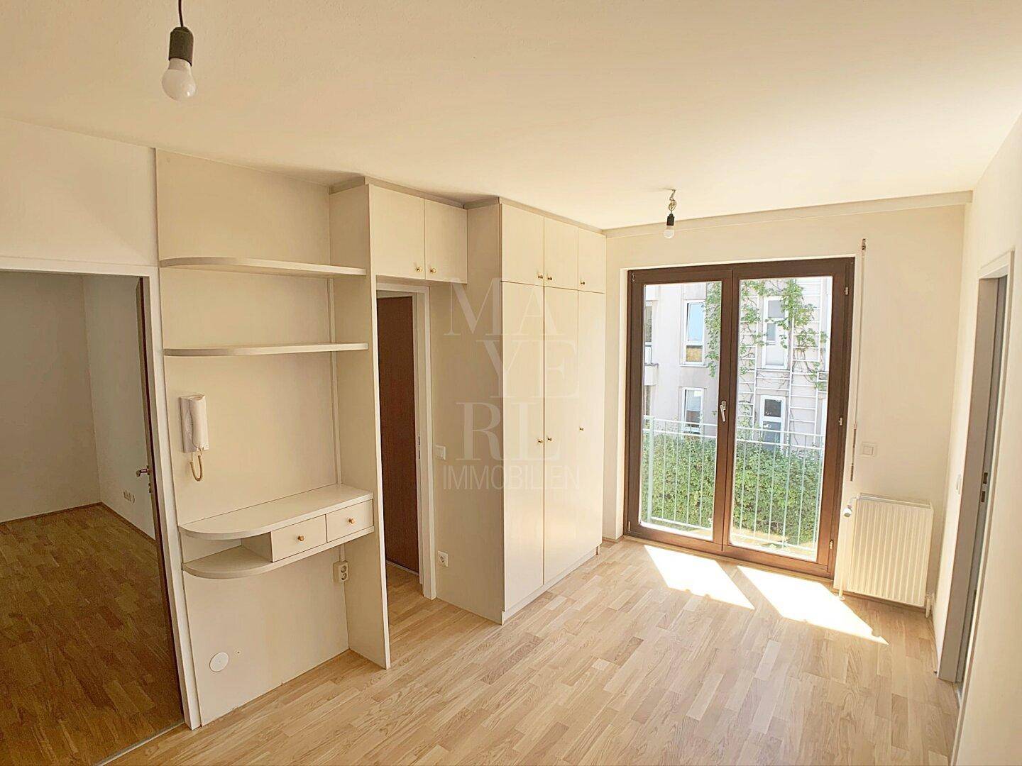Schlafzimmer mit Parkettboden, Einbauschränken und Zugang zu einem Balkon, hell und geräumig.