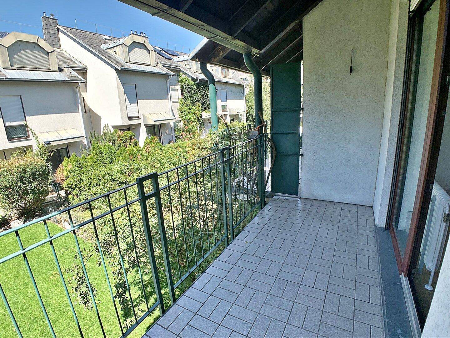 Balkon mit Fliesenboden und Metallgeländer, bietet einen grünen Blick auf die Umgebung.