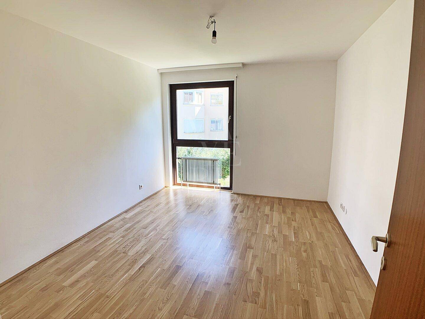 Geräumiges Schlafzimmer mit Parkettboden und Fenster mit Blick ins Grüne, gut belichtet.