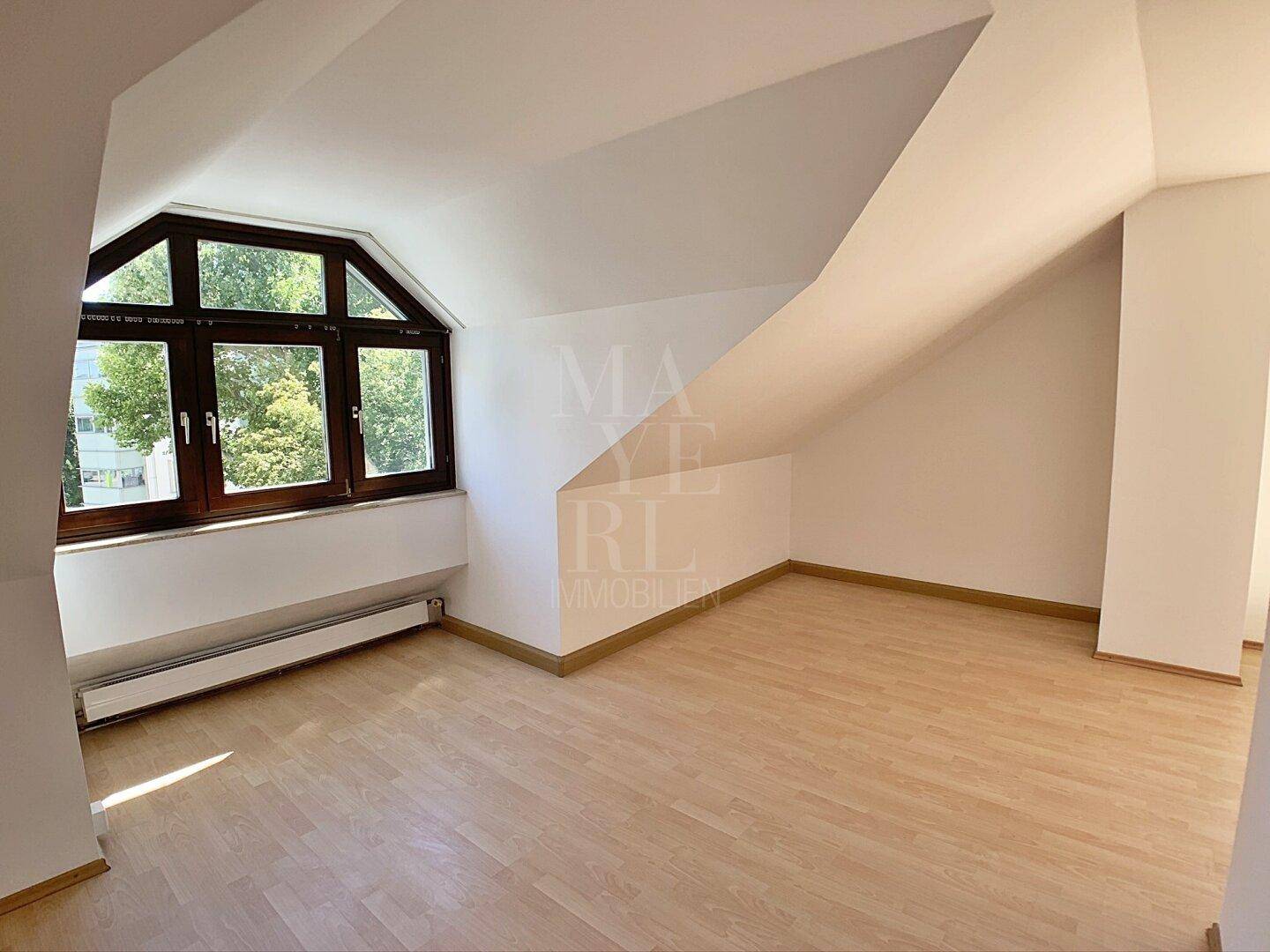 Dachgeschosszimmer mit schrägen Wänden und großen Fenstern, bietet viel Potenzial zur Gestaltung.