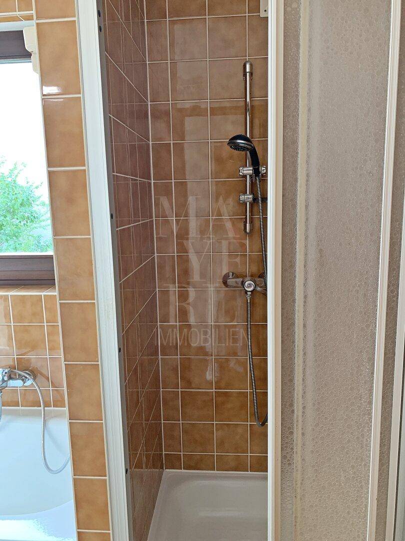 Duschbereich im Badezimmer mit braunen Fliesen und einfacher Duschkabine, funktional gestaltet.