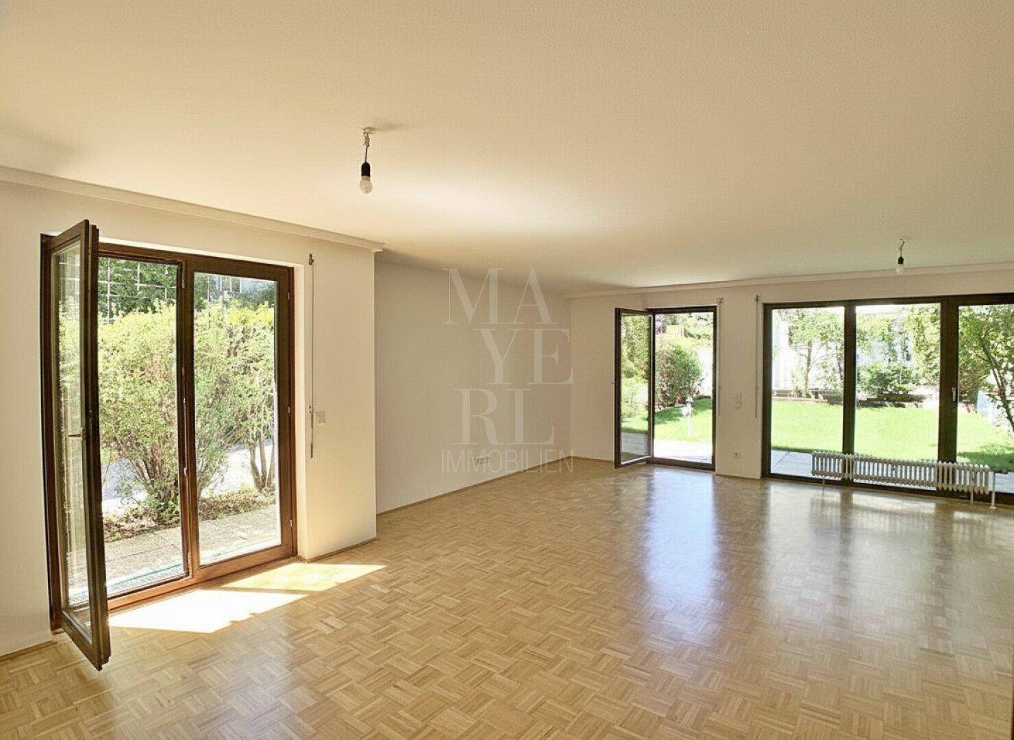 Helles Wohnzimmer mit Parkettboden und großen Fenstern zum Garten, ideal für offenes Wohnen.